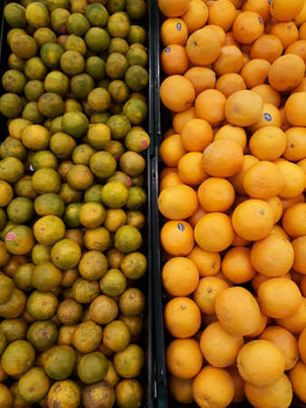 Mandarin or Orange? There are oranges and mandarins in a basket in the supermarket, which are divided in half.の写真素材