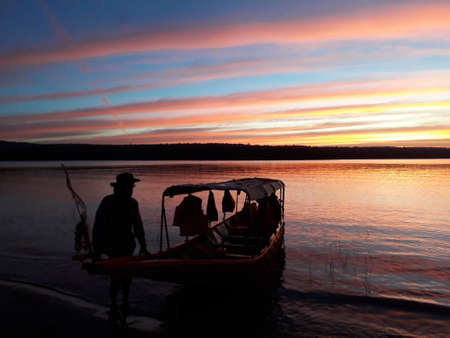 The evening sky by the dam with red and blue interspersed. There is a mountain behind.の写真素材