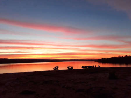 The evening sky by the dam with red and blue interspersed. There is a mountain behind.の写真素材