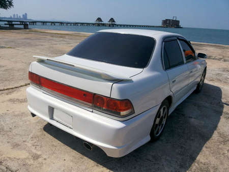 white sedan car by the sea - backの写真素材