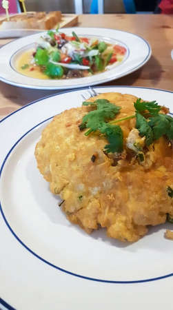 Fried eggs with clams sprinkled with coriander on a white plateの写真素材