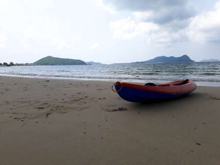 Rowing boat on a mountain beach behind cloudy skyの写真素材