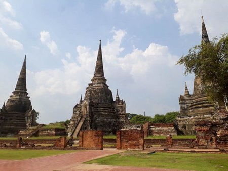 Three ancient pagodas with black stains There is a red brick wall in front.の写真素材