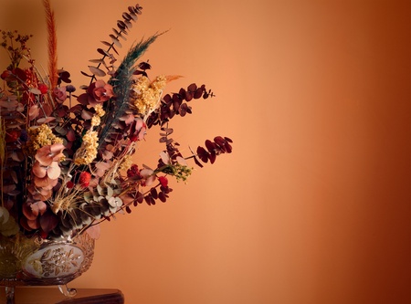 Warmth image with a dry flowers bouquet over an orange wallの写真素材