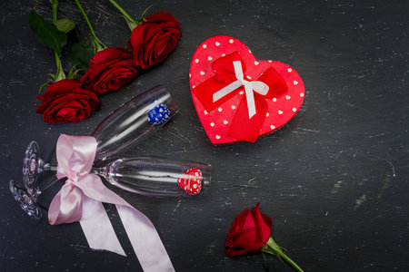 Valentine's Day. Composition: Three one red roses, two champagne glasses tied with a light pink...