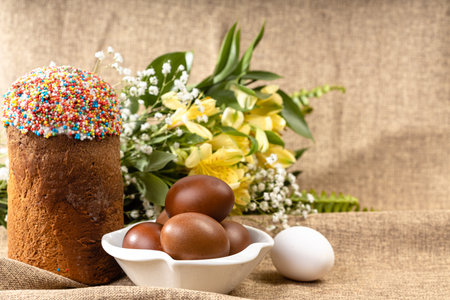 Easter composition of Easter cake, painted eggs and spring flowers on a background of burlap.