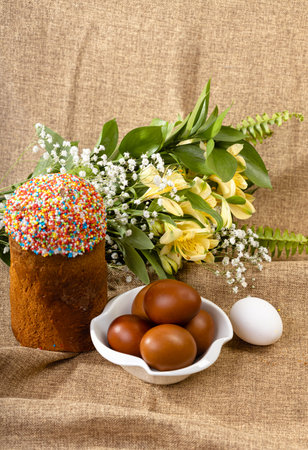 Easter composition of Easter cake, painted eggs and spring flowers on a background of burlap.