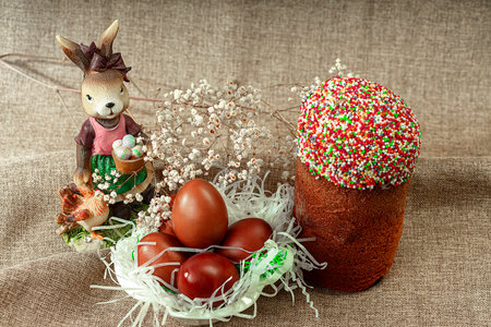 Easter cake, red painted Easter eggs, spring flowers and a bunny. Easter holiday decorations.の写真素材