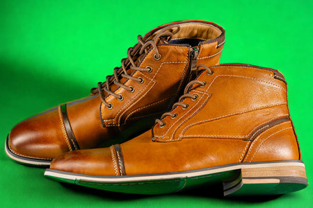 A pair of premium calfskin boots on a green background. Horizontal shot.