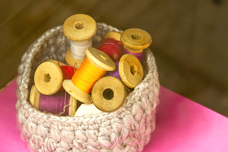 A box with spools of colored sewing thread is on the table. Sewing supplies.