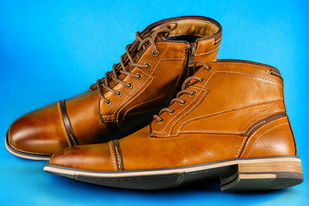 A pair of premium calfskin boots on a blue background. Horizontal shot.