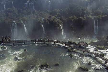 Tourists staying on Panoramic walkway overlooking Iguazu Falls, the border of Brazil and Argentinaの写真素材
