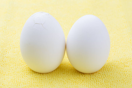 Two cracked eggs on yellow background
