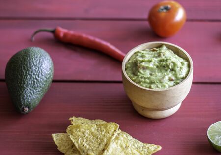 Guacamole and chips nachos. Red background. Mexican cuisineの写真素材