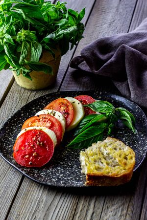 Italian caprese salad with mozzarella and tomatoes. Wooden background. Healthy food.の写真素材