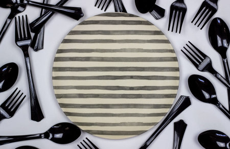 Forks and spoons next to the plate on a white background. Minimal concept