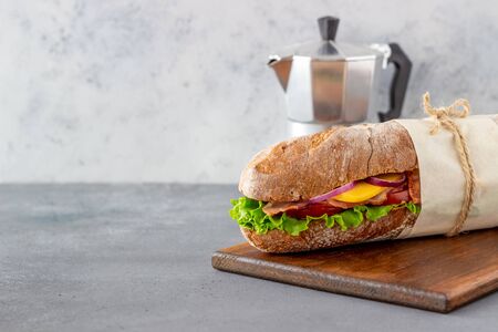 A sandwich of dark bread with salad, bacon, tomatoes, cheese and onions. Baguette. Breakfast. Fast food. Healthy eating. Recipes.の写真素材