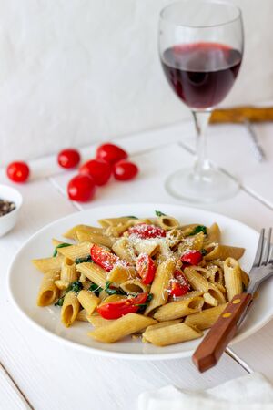 Italian penne pasta with tomatoes, spinach, parmesan cheese, garlic and nuts. Healthy eating. Vegetarian foodの写真素材