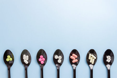 Spoons with pills on a blue background. Medicine. Medication. Health.
