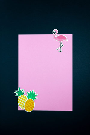 Paper flamingo and pineapples on pink black background. Minimal concept. Copy space.