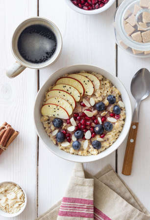 Oatmeal porridge with apple, pomegranate, blueberries and almonds. Healthy eating. Vegetarian food. Breakfastの写真素材