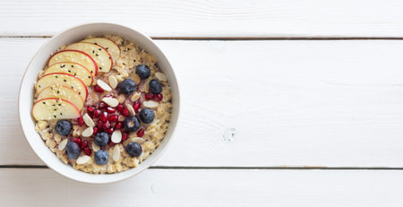 Oatmeal porridge with apple, pomegranate, blueberries and almonds. Healthy eating. Vegetarian food. Breakfastの写真素材