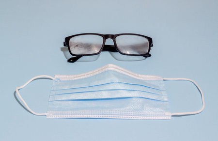 Medical mask and sweaty glasses on a blue background. Pandemic