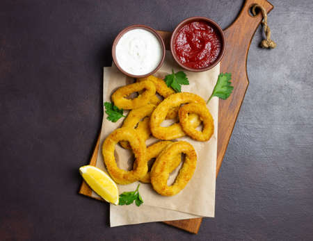 Fried squid rings with two sauces, lemon and herbs. fast food. Appetizerの写真素材