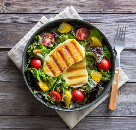 Salad with grilled halloumi cheese, tomatoes, orange and pumpkin seeds. healthy eating. Vegetarian food. Keto dietの写真素材