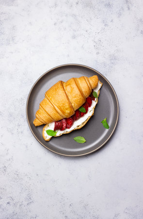 Croissant with strawberries, white cheese and mint. breakfast. Vegetarian foodの写真素材