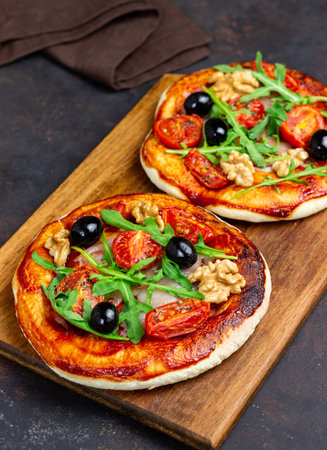 Two pizzas with mozzarella cheese, nuts, arugula, tomatoes and olives. Italian food. Vegetarian foodの写真素材