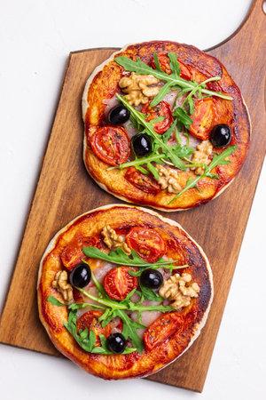 Two pizzas with mozzarella cheese, nuts, arugula, tomatoes and olives. Italian food. Vegetarian foodの写真素材