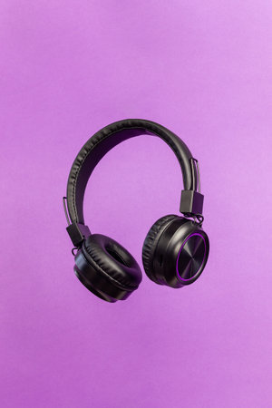 Black headphones on a purple background. Minimal concept. Mock-up. Music. Levitation.の写真素材