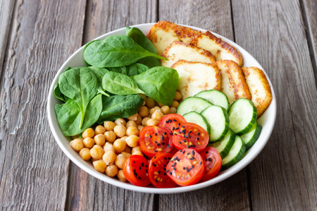 Bowl with grilled Halloumi cheese, spinach, chickpeas, tomatoes and cucumbers. Healthy eating. Vegetarian food. Dietの写真素材