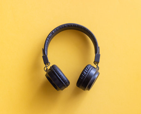 Black headphones on a yellow background. Minimal concept. Mock-up. Music.の写真素材