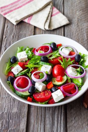 Greek salad with feta cheese, tomatoes, onion, cucumbers, peppers and olives. Healthy eating. Vegetarian foodの写真素材