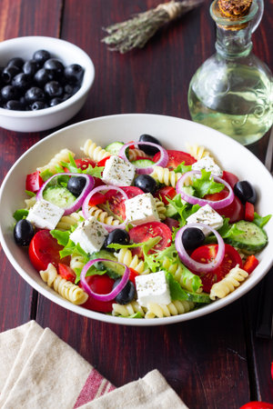 Greek pasta salad with feta cheese, tomatoes, onion, cucumbers, peppers and olives. Healthy eating. Vegetarian foodの写真素材