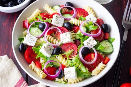 Greek pasta salad with feta cheese, tomatoes, onion, cucumbers, peppers and olives. Healthy eating. Vegetarian foodの写真素材