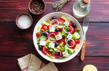 Greek pasta salad with feta cheese, tomatoes, onion, cucumbers, peppers and olives. Healthy eating. Vegetarian foodの写真素材