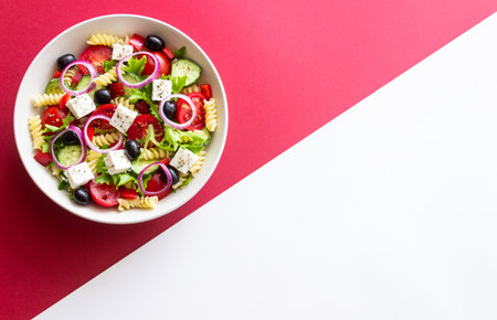 Greek pasta salad with feta cheese, tomatoes, onion, cucumbers, peppers and olives. Healthy eating. Vegetarian foodの写真素材