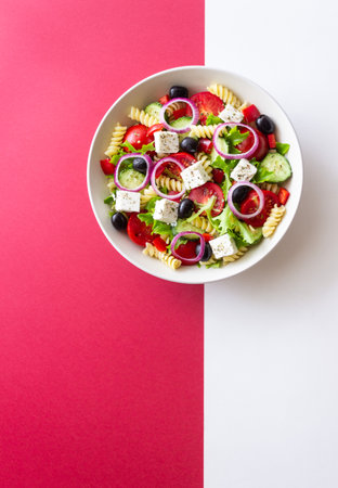 Greek pasta salad with feta cheese, tomatoes, onion, cucumbers, peppers and olives. Healthy eating. Vegetarian foodの写真素材