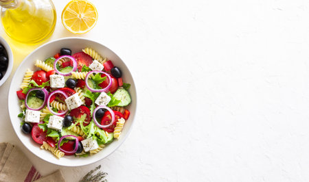 Greek pasta salad with feta cheese, tomatoes, onion, cucumbers, peppers and olives. Healthy eating. Vegetarian foodの写真素材