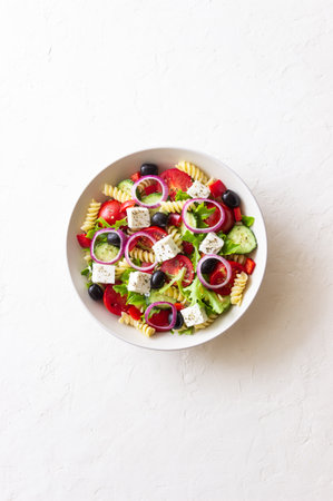Greek pasta salad with feta cheese, tomatoes, onion, cucumbers, peppers and olives. Healthy eating. Vegetarian foodの写真素材