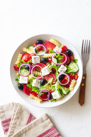 Greek pasta salad with feta cheese, tomatoes, onion, cucumbers, peppers and olives. Healthy eating. Vegetarian foodの写真素材