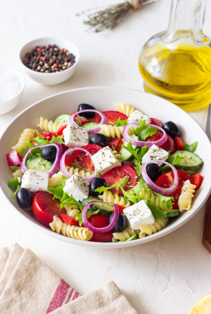 Greek pasta salad with feta cheese, tomatoes, onion, cucumbers, peppers and olives. Healthy eating. Vegetarian foodの写真素材