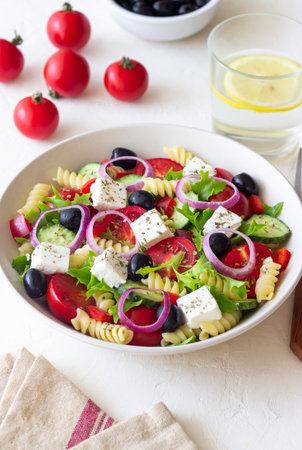 Greek pasta salad with feta cheese, tomatoes, onion, cucumbers, peppers and olives. Healthy eating. Vegetarian foodの写真素材