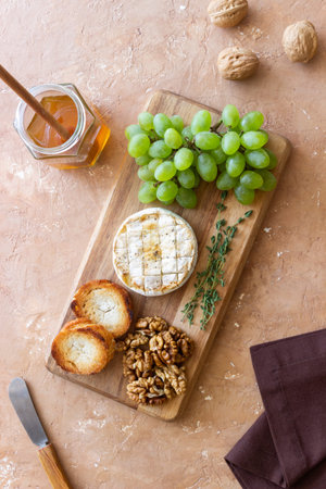 Baked brie cheese with grapes, thyme, baguette and nuts. French cuisine. Vegetarian foodの写真素材