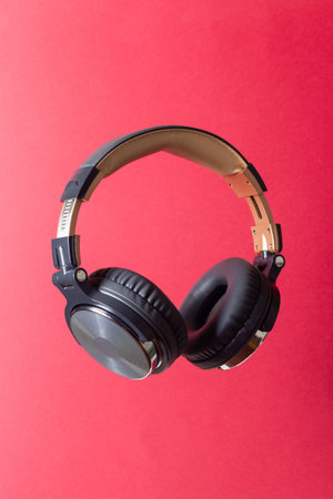 Black headphones on a red background. Minimal concept. Mock-up. Music. Levitation.の写真素材