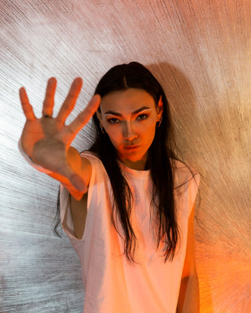 Asian androgynous man with long hair posing and holding hand in front of his face