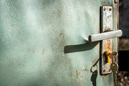 Rusty handle of an old worn open door with a key on a blurred background. Retro, povertyの写真素材
